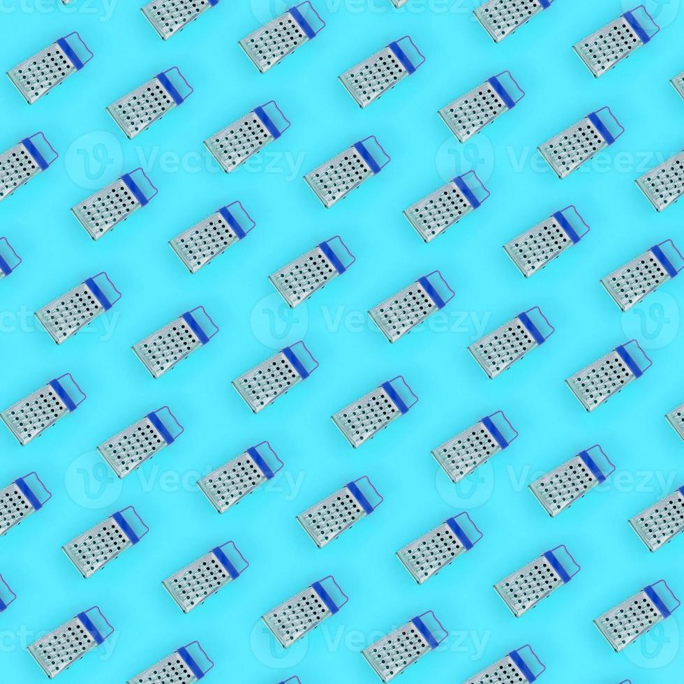 Small stainless steel graters lies on a pastel colored paper. Kitchen accessories. Tools for cooking. Flat lay top view photo
