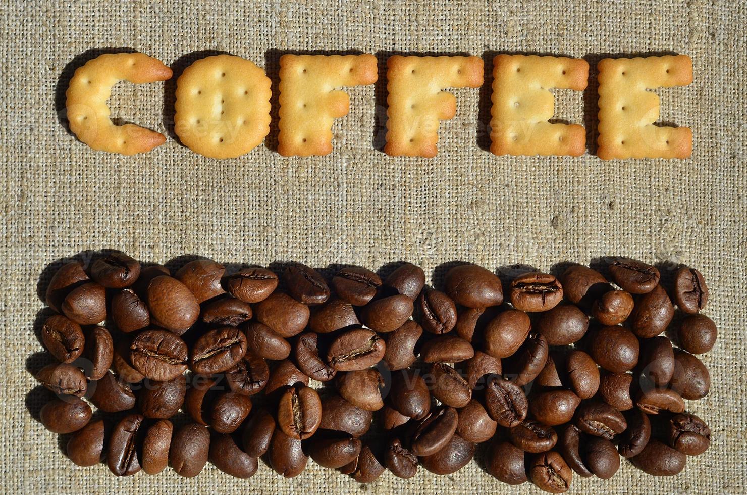 Coffee. The word from the edible letters lies on the gray canvas with coffee beans photo