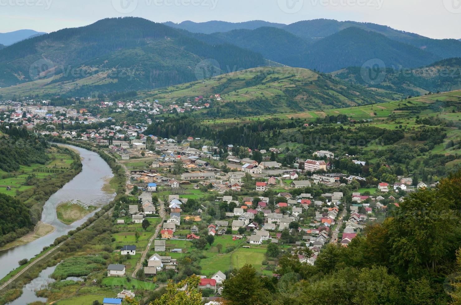 una hermosa vista del pueblo de mezhgorye, región de los cárpatos. muchos edificios residenciales rodeados de montañas altas y ríos largos foto