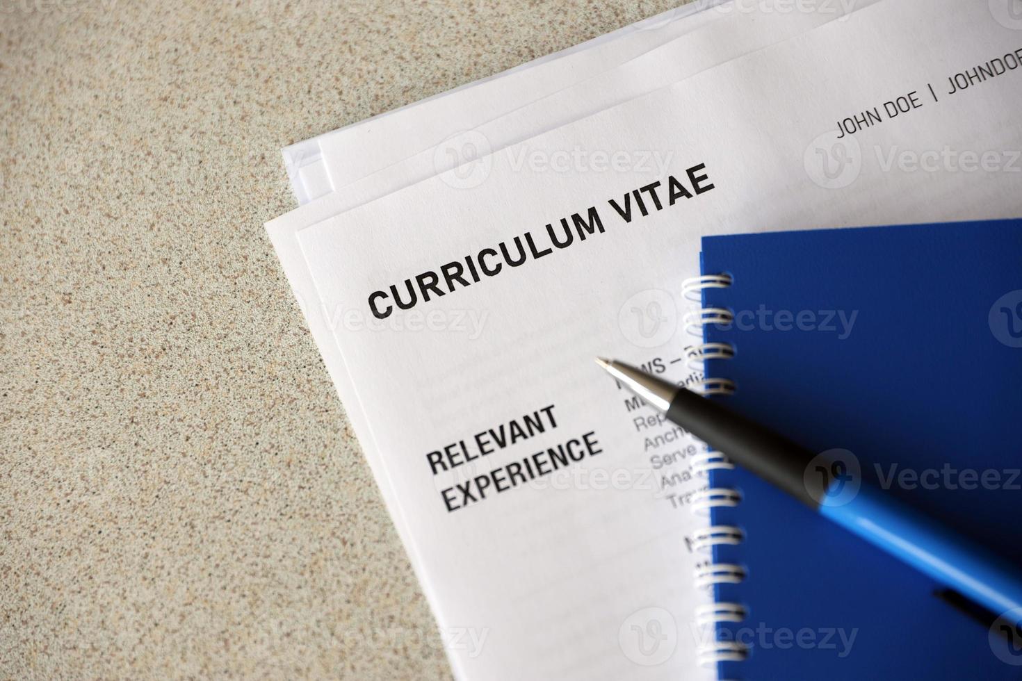 Top view of stack of office documents including resume and cv forms on the desk close to pen and notepad. Job seeking process. Hunting for workplace photo