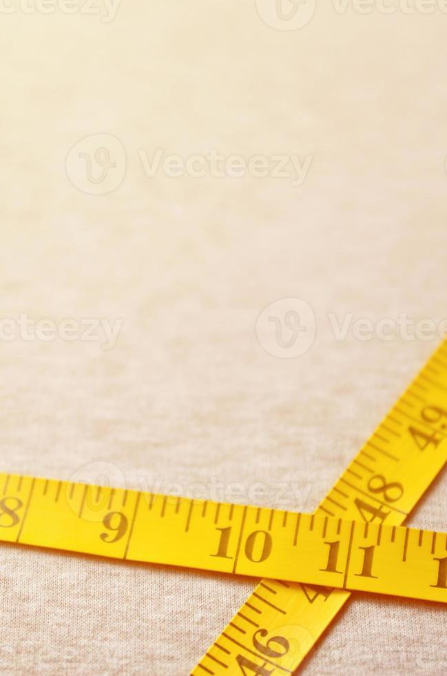 Yellow measuring tape lies on a gray knitted fabric photo