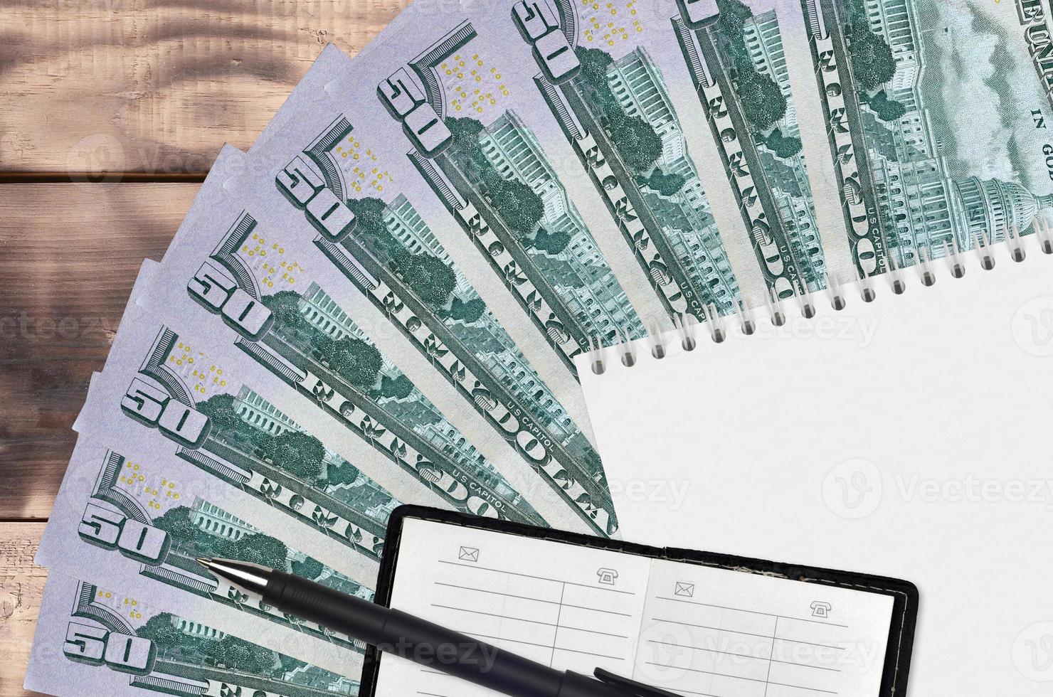 50 US dollars bills fan and notepad with contact book and black pen. Concept of financial planning and business strategy photo