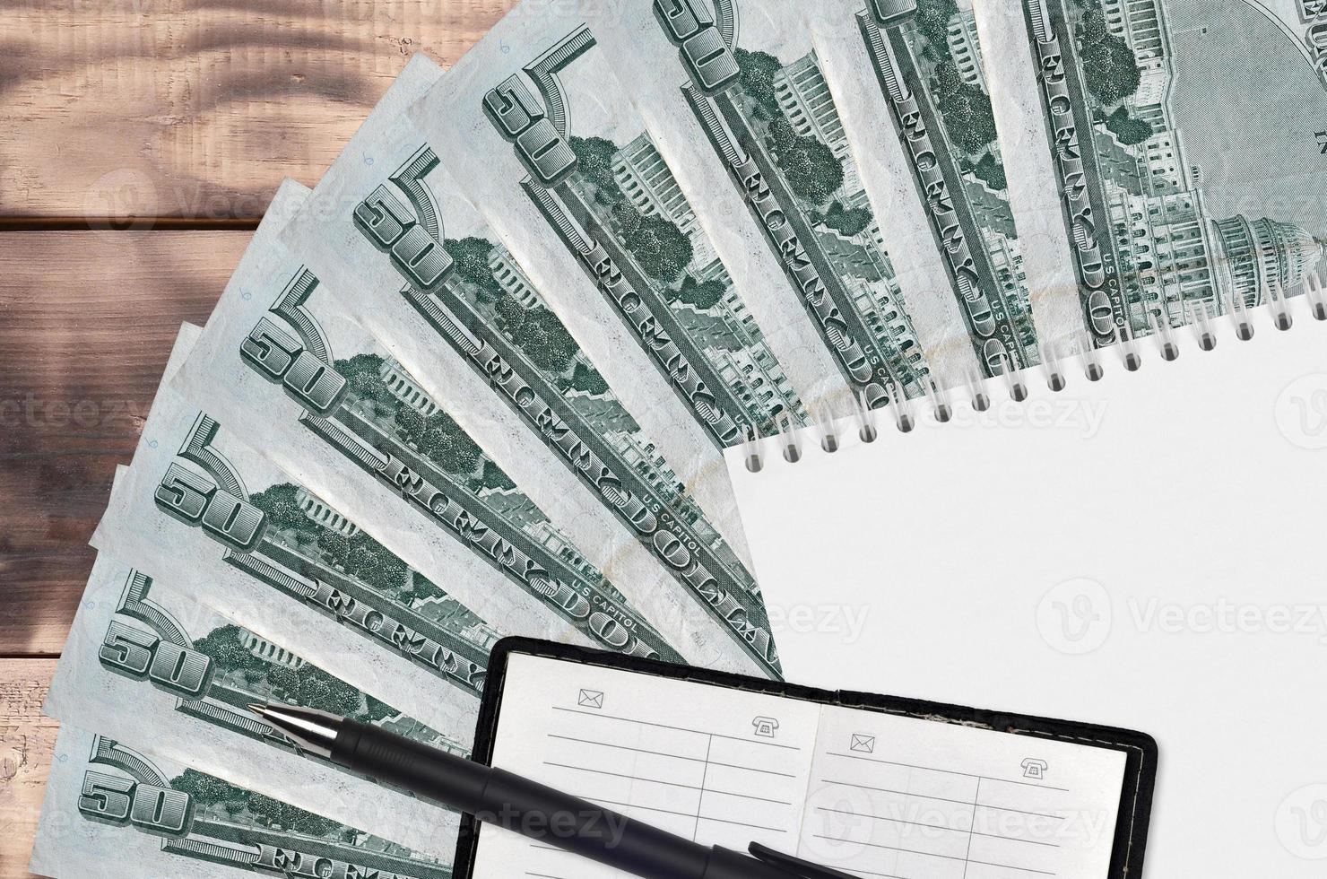 50 US dollars bills fan and notepad with contact book and black pen. Concept of financial planning and business strategy photo