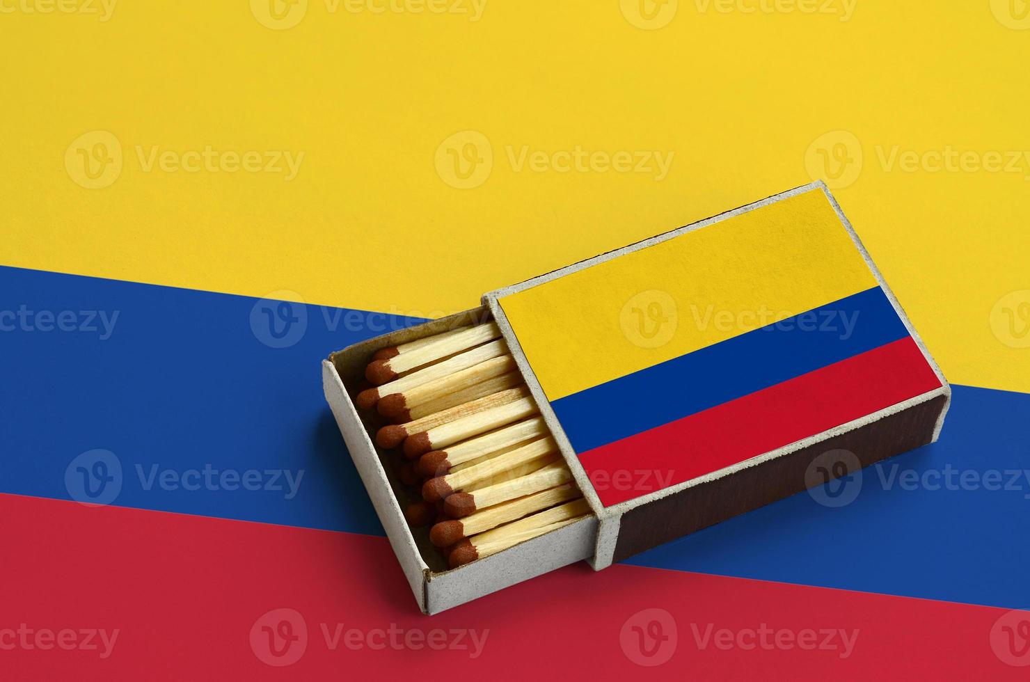 Colombia flag is shown in an open matchbox, which is filled with matches and lies on a large flag photo