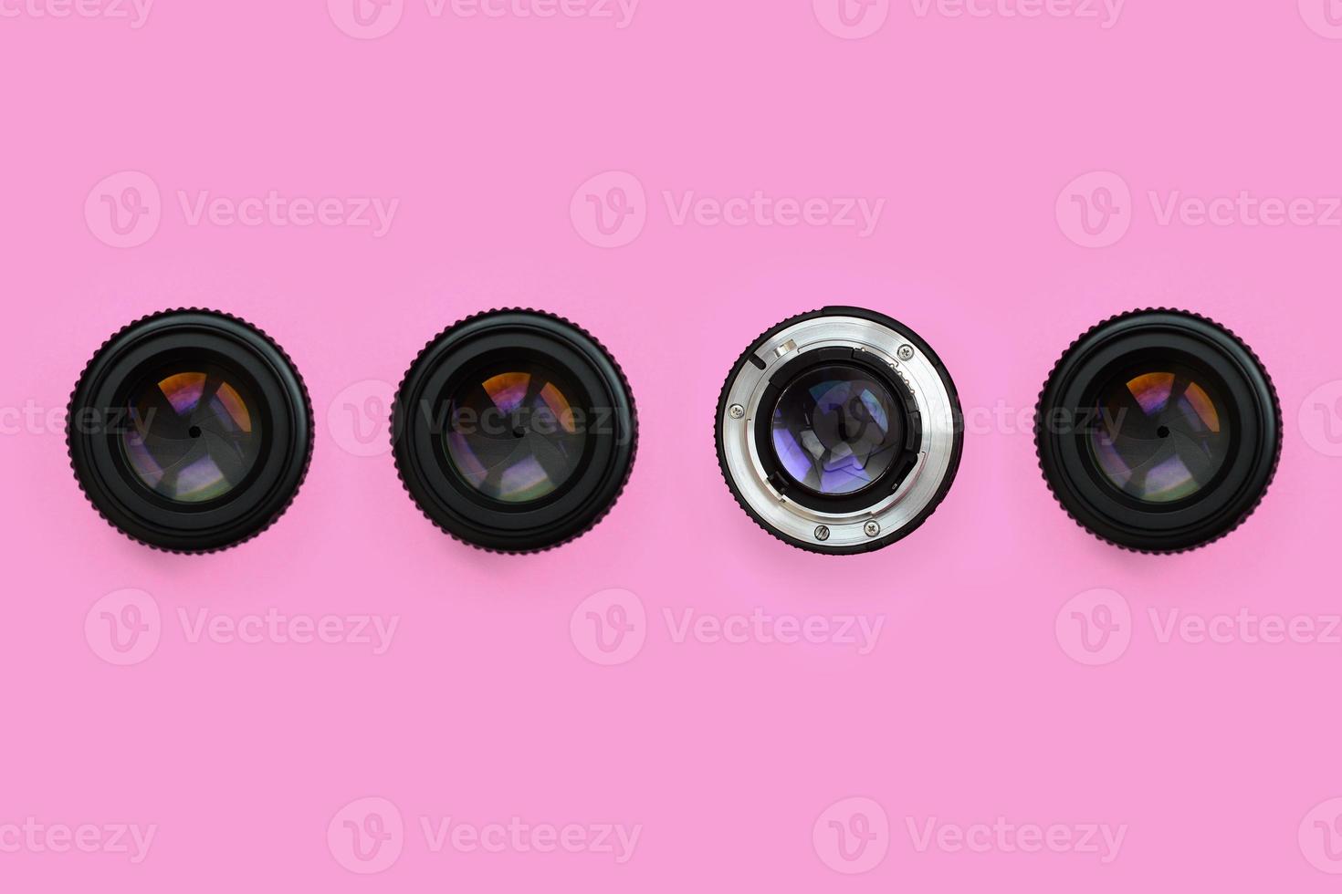 A few camera lenses with a closed aperture lie on texture background of fashion pastel pink color paper in minimal concept. Abstract trendy pattern photo