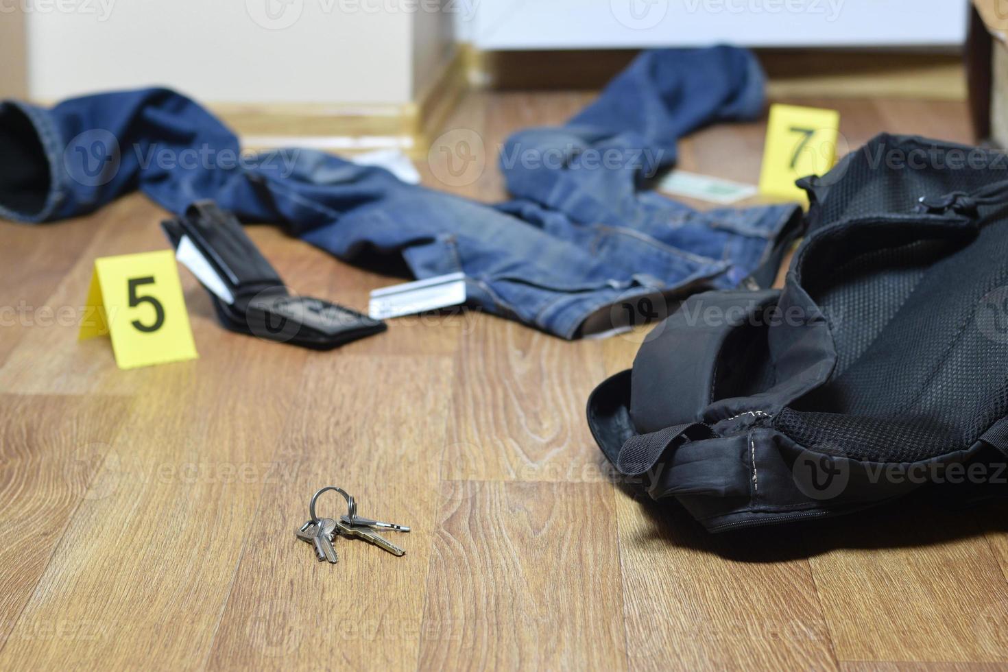Crime scene investigation - numbering of evidences after the murder in the apartment. Keys, wallet and clothes with evidence markers photo