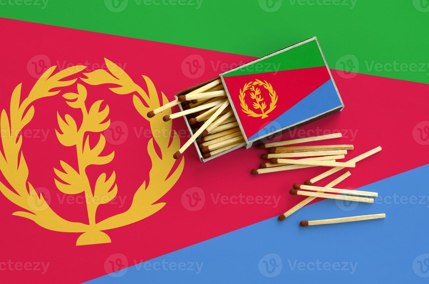 Eritrea flag is shown on an open matchbox, from which several matches fall and lies on a large flag photo