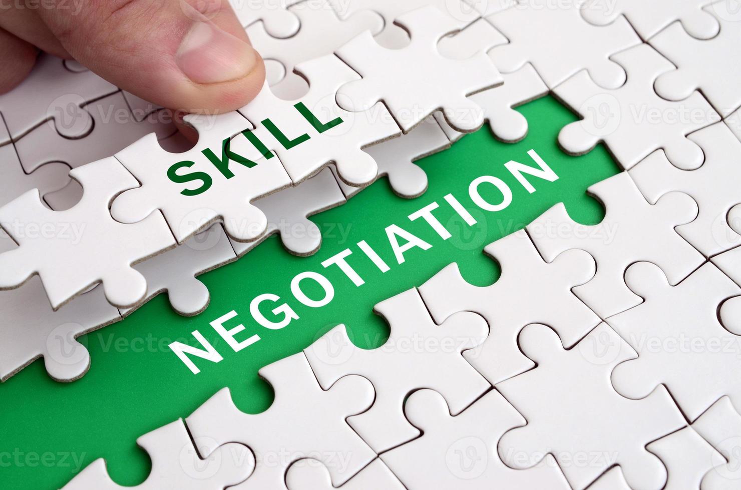 The human hand fills the last missing elements of the surface from the jigsaw puzzle. Image with words skill and negotiation photo