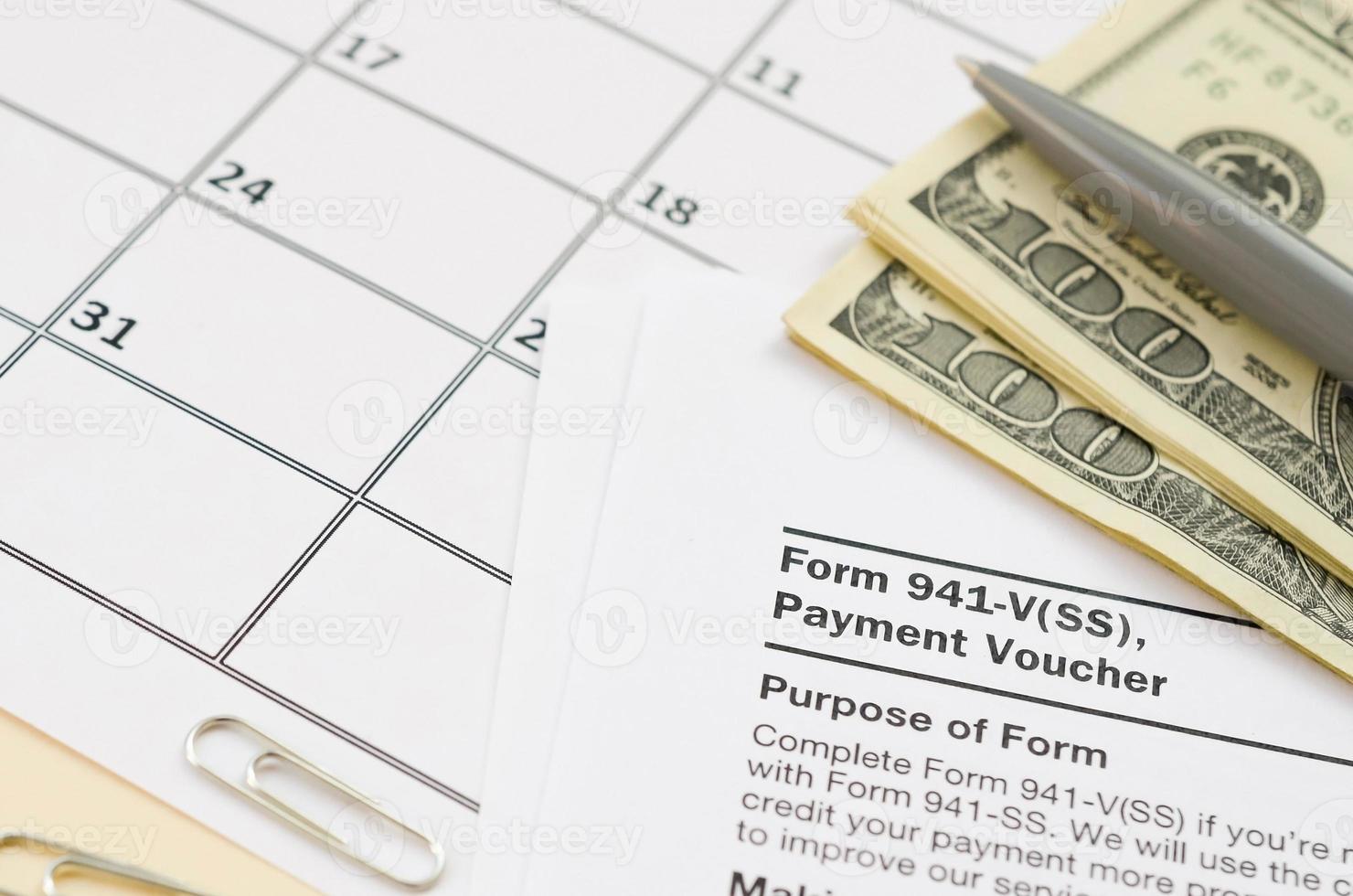 el cupón de pago del formulario 941-v del irs se encuentra en blanco con bolígrafo y muchos billetes de cien dólares en la página del calendario foto