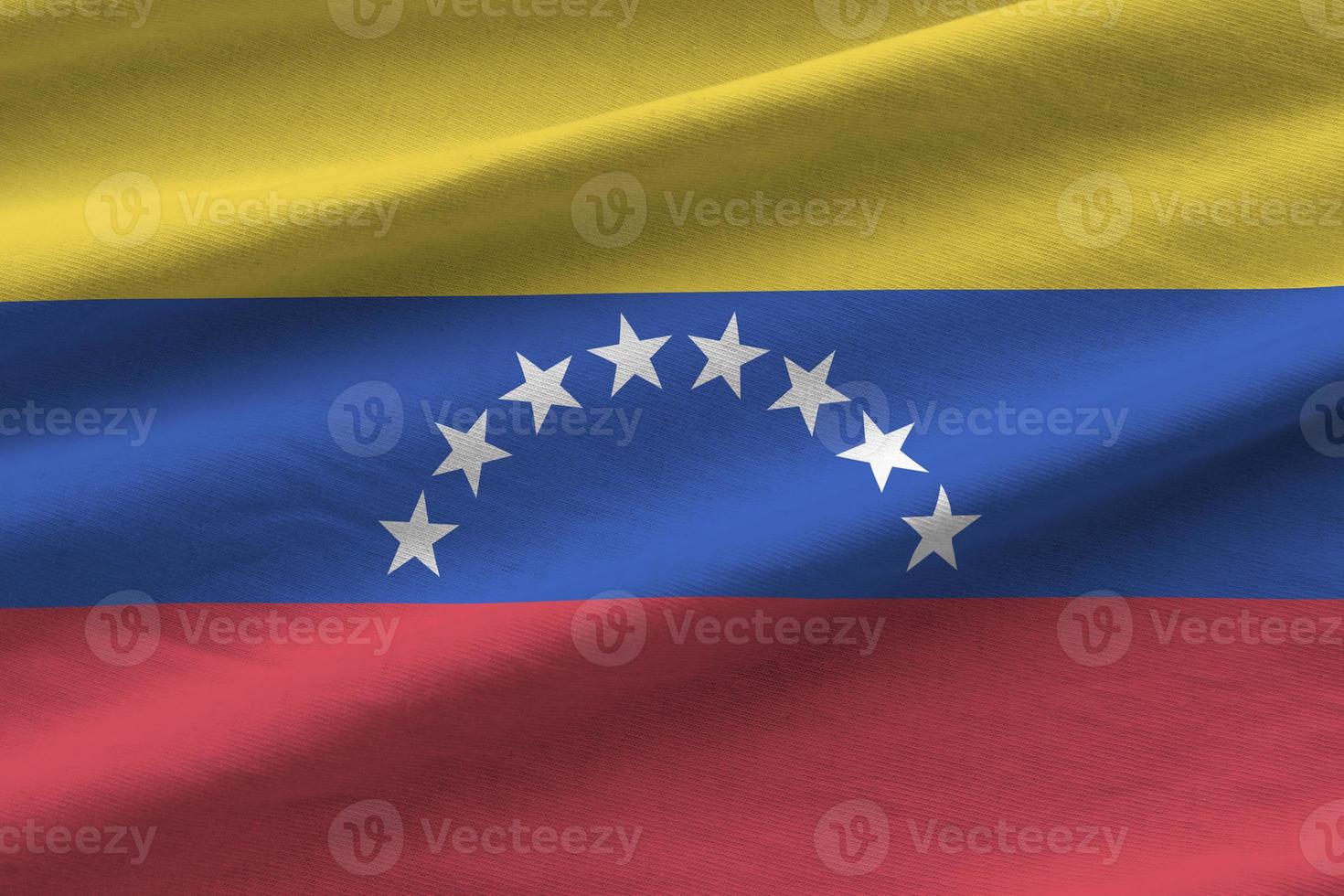 Venezuela flag with big folds waving close up under the studio light indoors. The official symbols and colors in banner photo