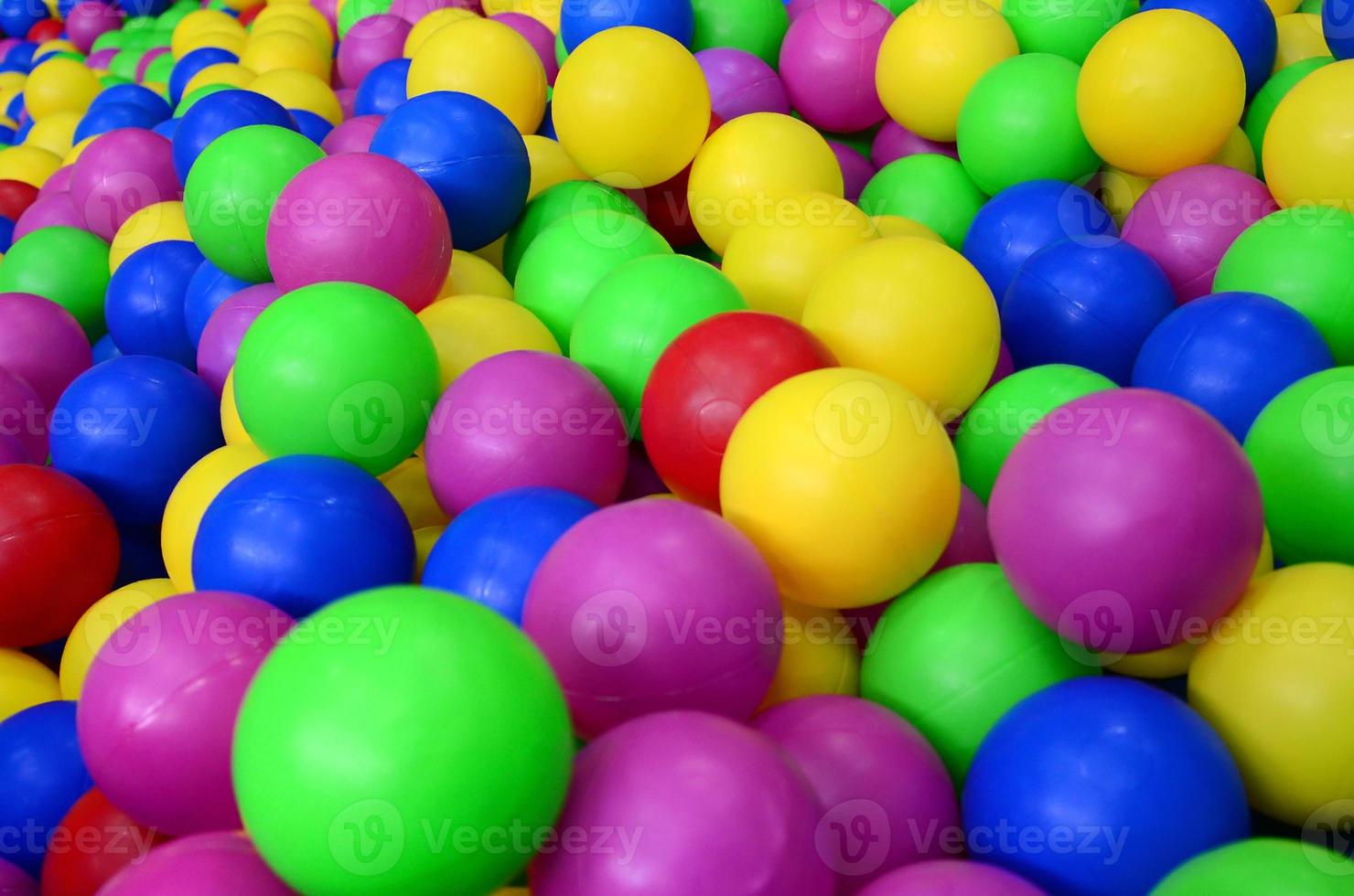 Many colorful plastic balls in a kids' ballpit at a playground. Close up pattern photo
