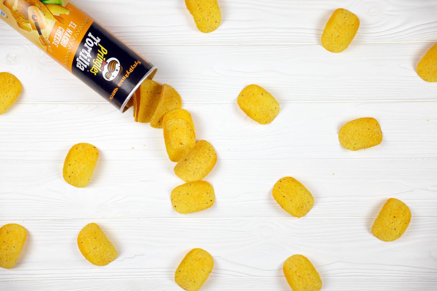 KHARKOV, UKRAINE - MAY 3, 2022 Pringles el nacho cheese flavour. Cardboard tube can with Pringles potato chips on white table. Pringles is a brand of snack chips owned by Kellogg Company photo