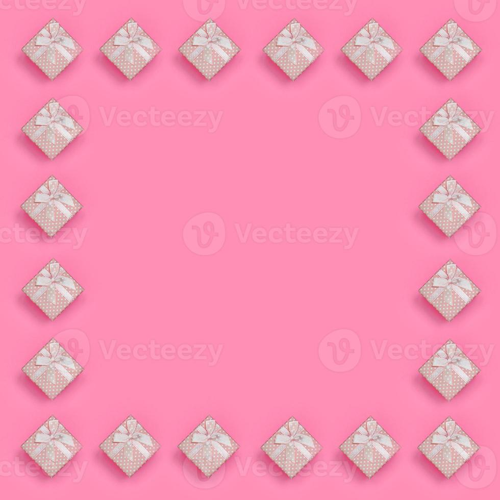 Frame of pink gift boxes lies on texture background of fashion pastel pink color paper in minimal concept. Abstract trendy pattern photo