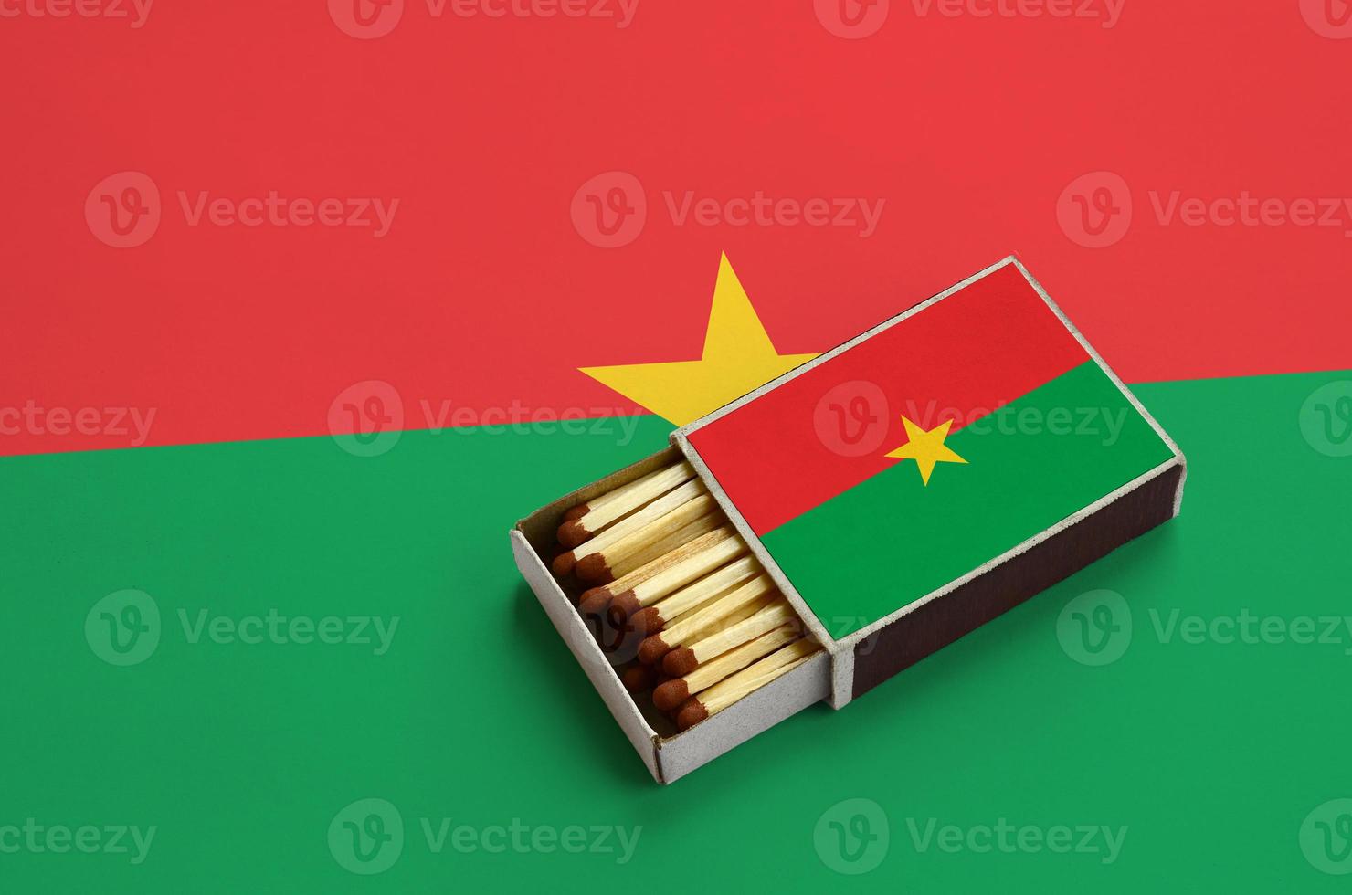 Burkina Faso flag is shown in an open matchbox, which is filled with matches and lies on a large flag photo