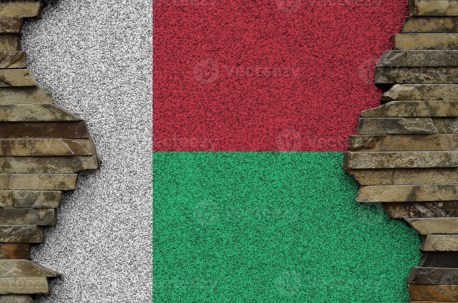 Madagascar flag depicted in paint colors on old stone wall closeup. Textured banner on rock wall background photo
