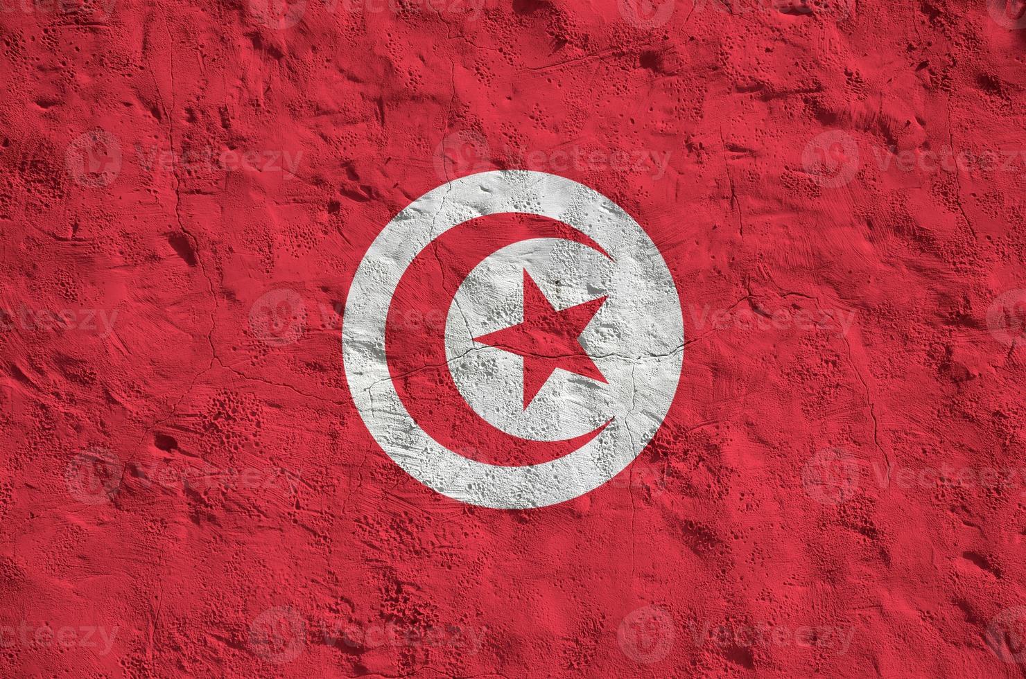 Tunisia flag depicted in bright paint colors on old relief plastering wall. Textured banner on rough background photo