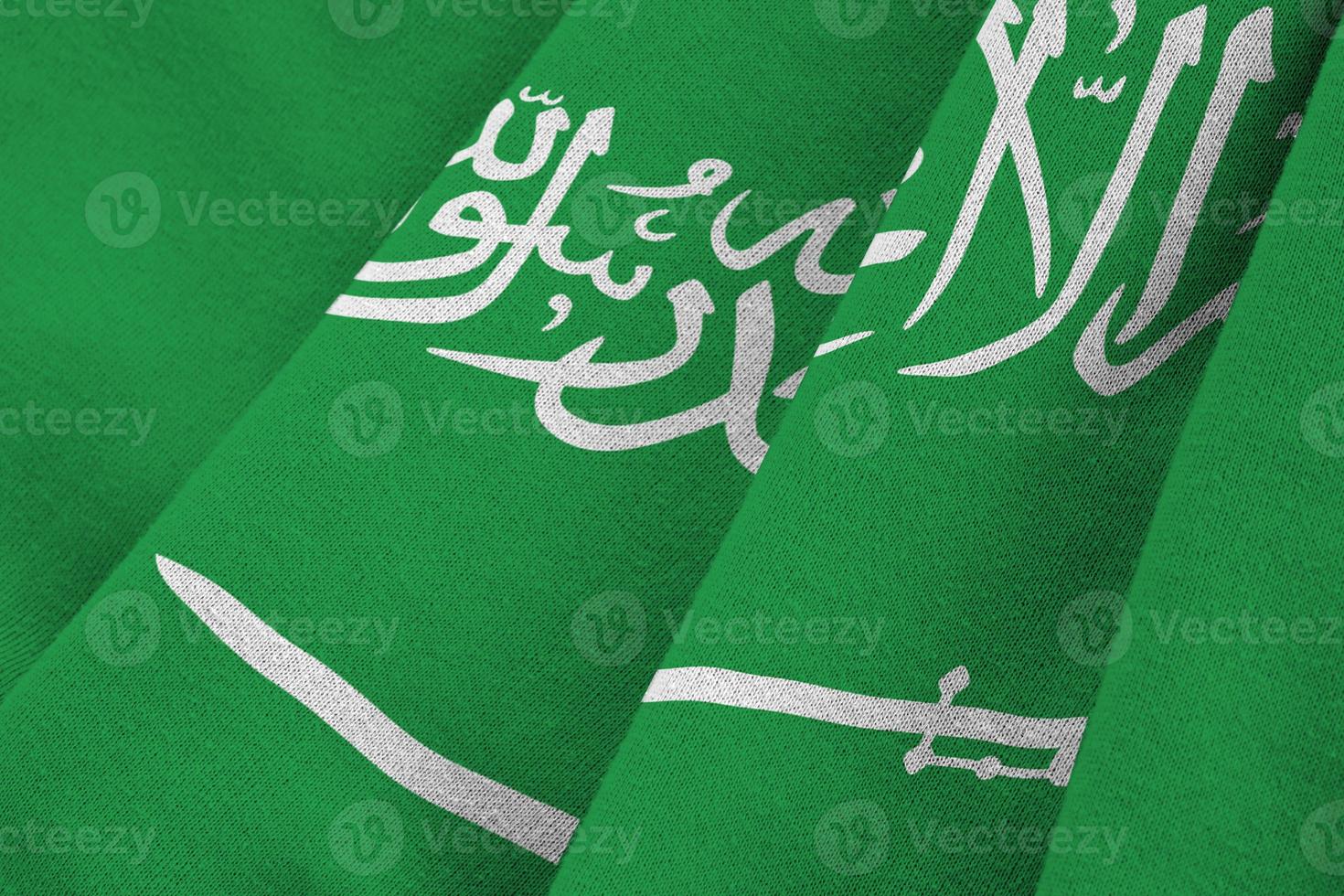 Saudi Arabia flag with big folds waving close up under the studio light indoors. The official symbols and colors in banner photo