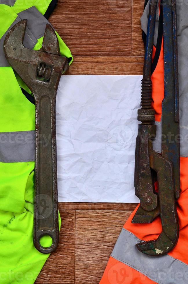 llaves ajustables y mentiras de papel de una camisa de trabajador de señal naranja y verde foto