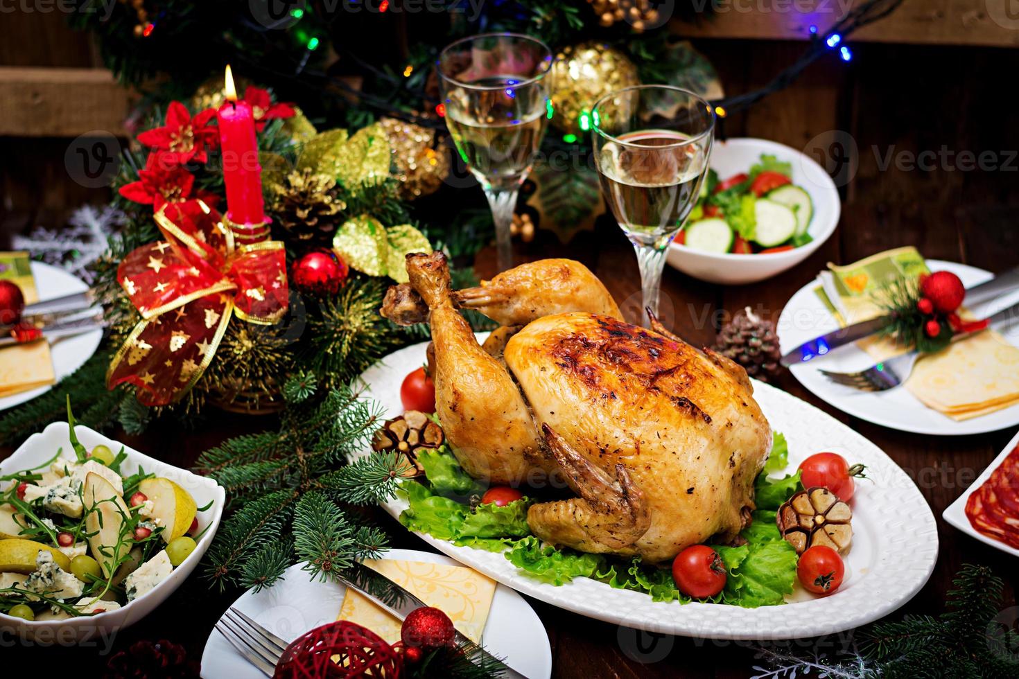 Baked turkey or chicken. The Christmas table is served with a turkey, decorated with bright tinsel and candles. Fried chicken, table. Christmas dinner. photo