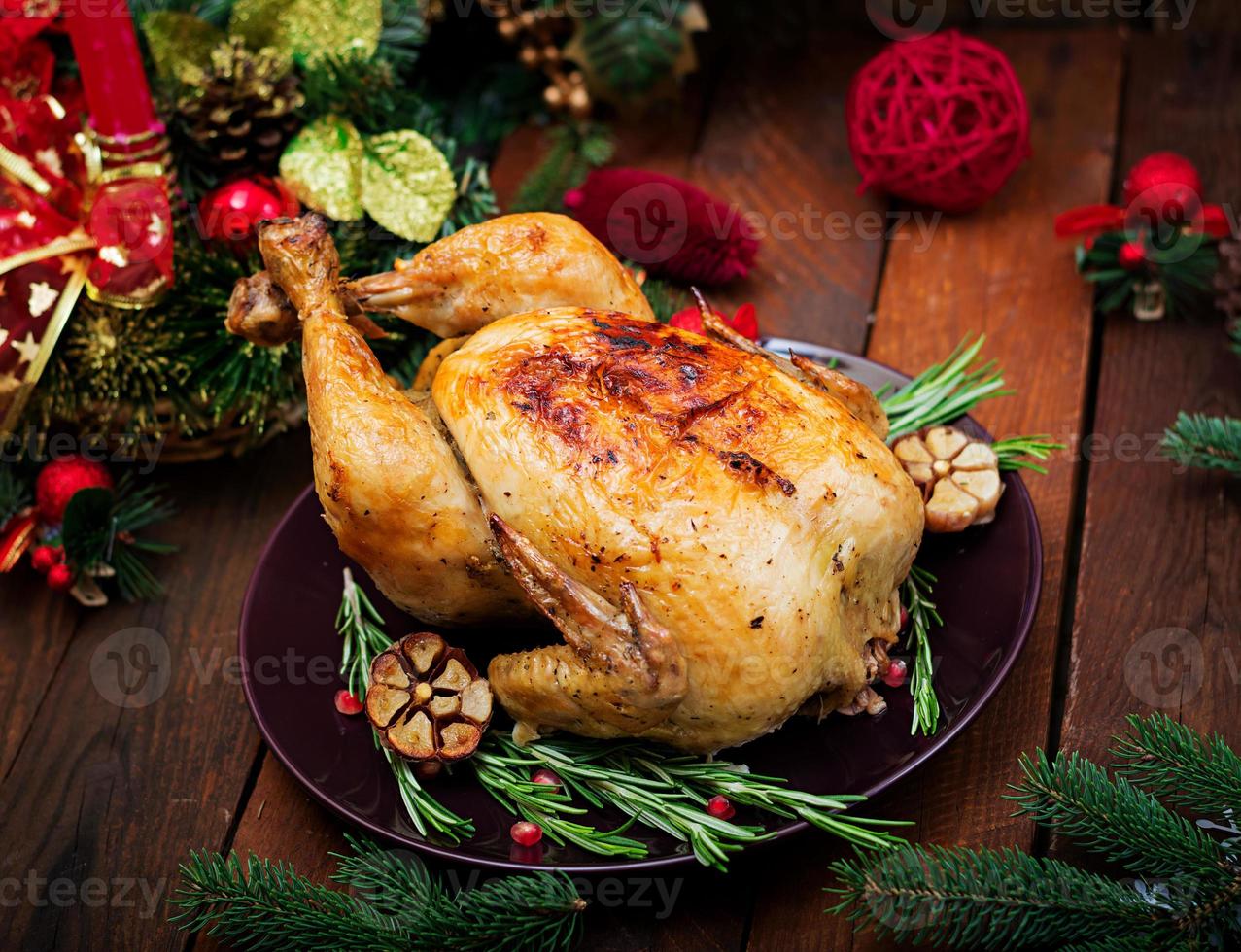 Baked turkey or chicken. The Christmas table is served with a turkey, decorated with bright tinsel and candles. Fried chicken, table. Christmas dinner. photo