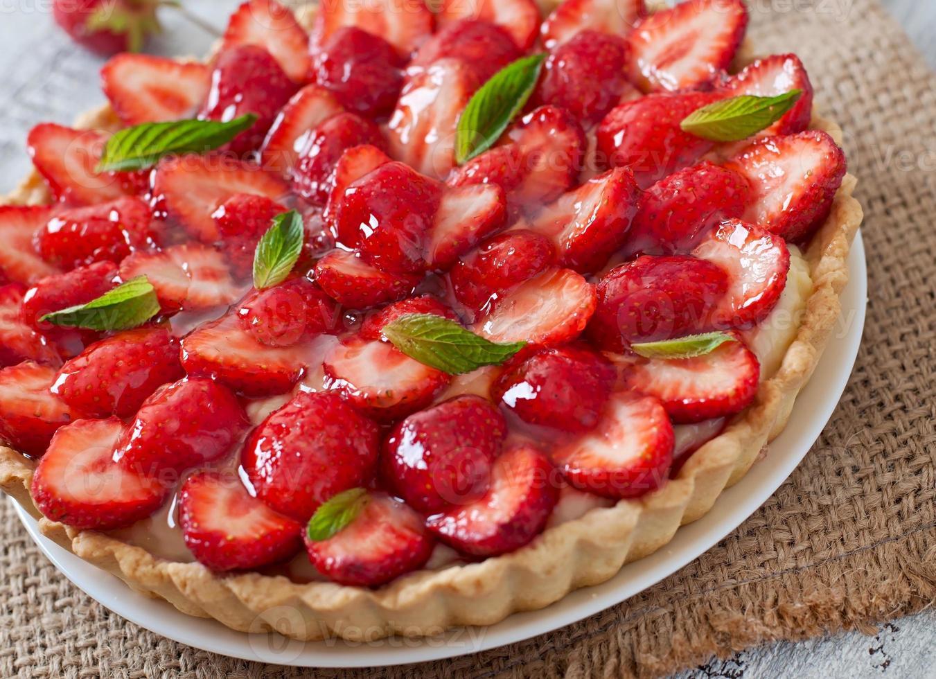 Tart with strawberries and whipped cream decorated with mint leaves photo