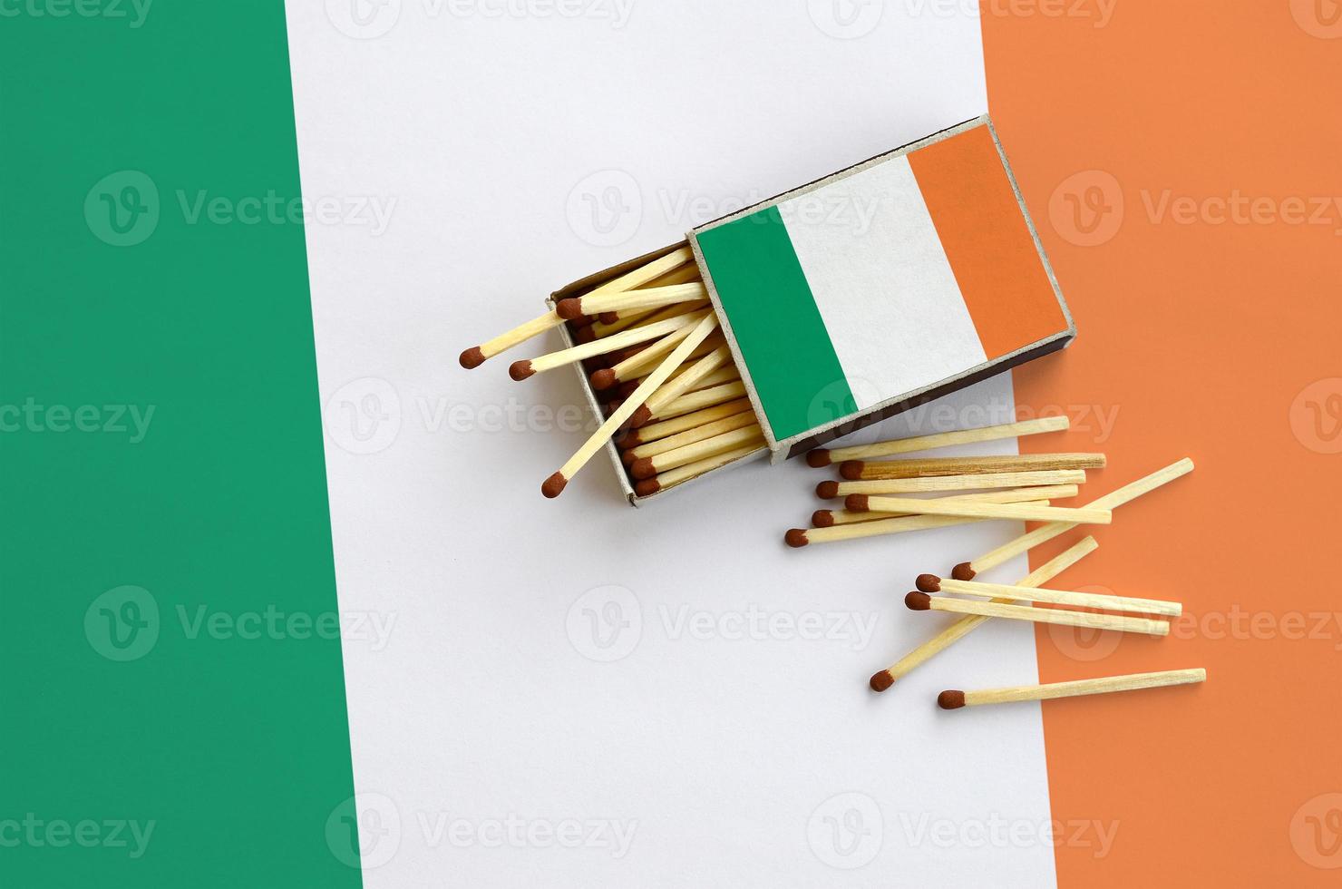 Ireland flag is shown on an open matchbox, from which several matches fall and lies on a large flag photo