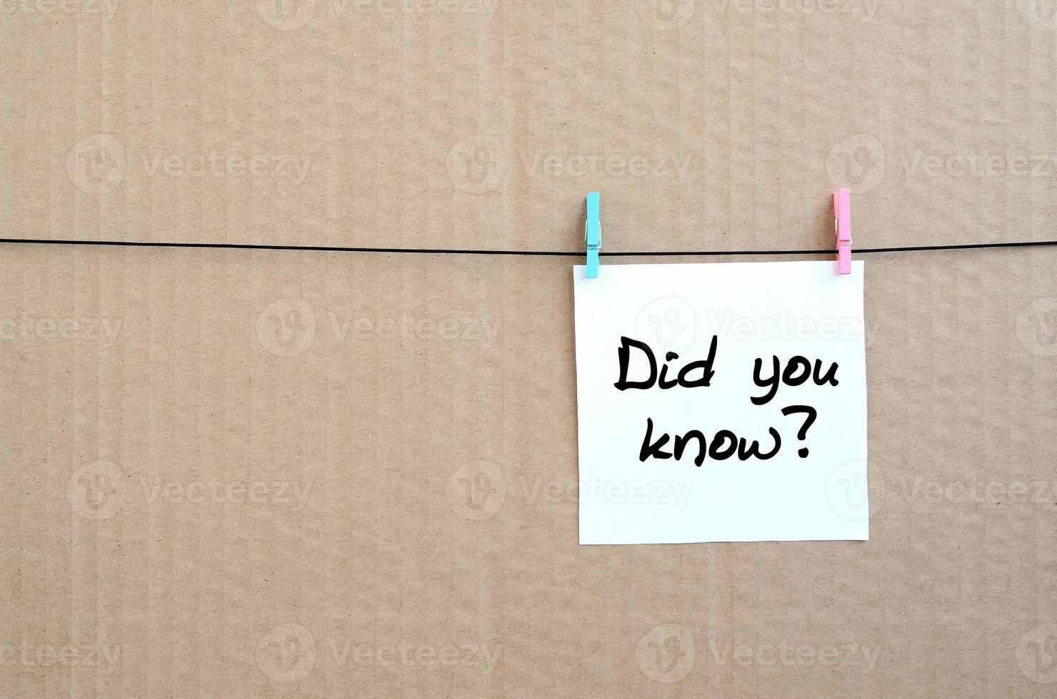 Did you know Note is written on a white sticker that hangs with a clothespin on a rope on a background of brown cardboard photo