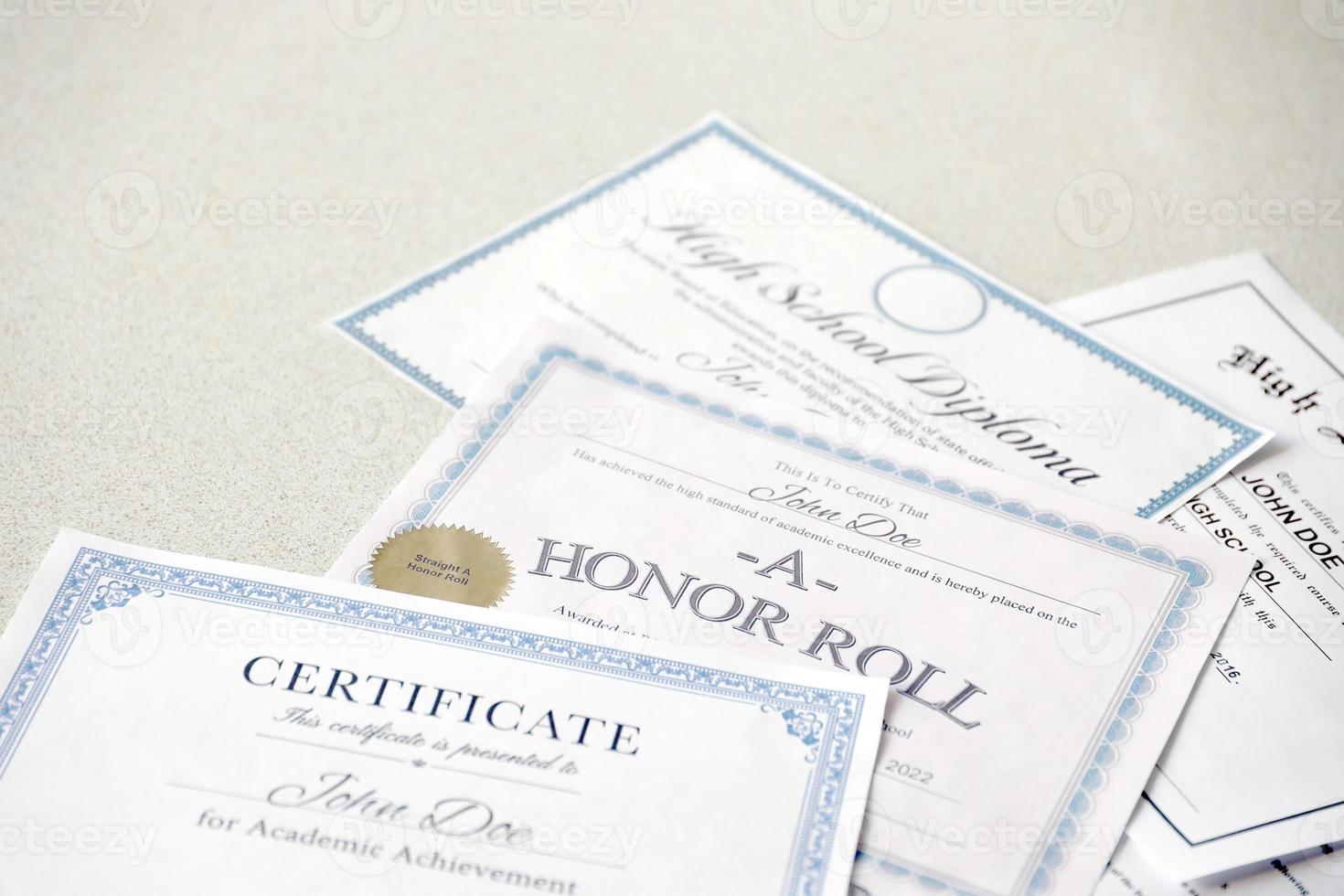 A honor roll recognition, certificate of achievement and high school diploma lies on table. Education documents photo
