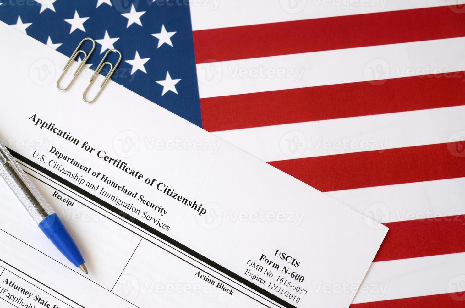 N-600 Application for Certificate of Citizenship blank form lies on United States flag with blue pen from Department of Homeland Security photo