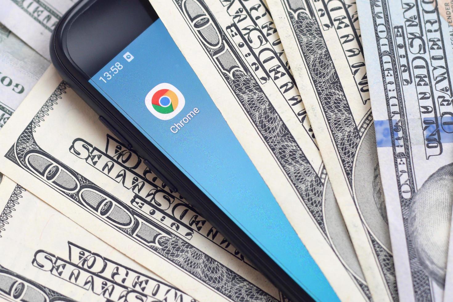 KHARKOV, UKRAINE - MAY 3, 2021 Smartphone screen with Google chrome app and lot of hundred dollar bills. Business and social networking concept photo