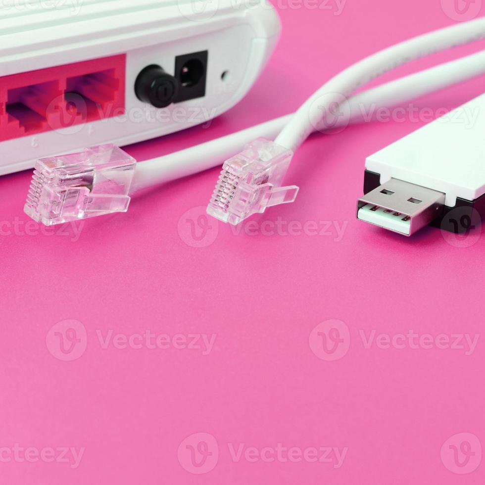 Internet router, portable USB wi-fi adapter and internet cable plugs lie on a bright pink background. Items required for internet photo
