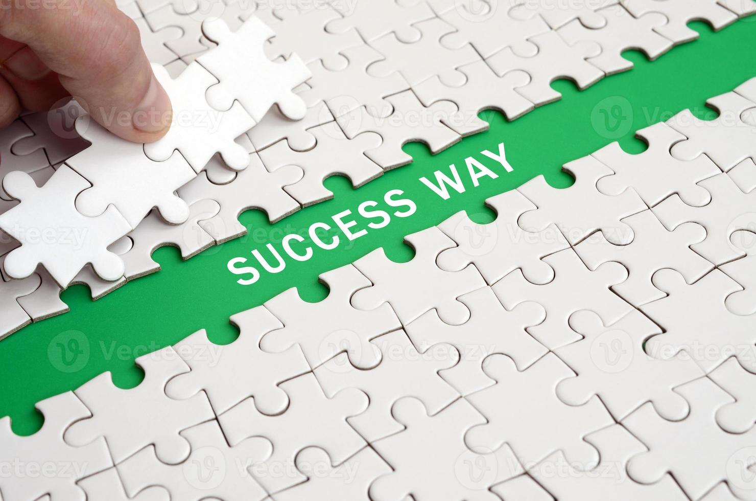 The human hand paves the way to the surface of the jigsaw puzzle, forming a green space with inscription. Success way photo