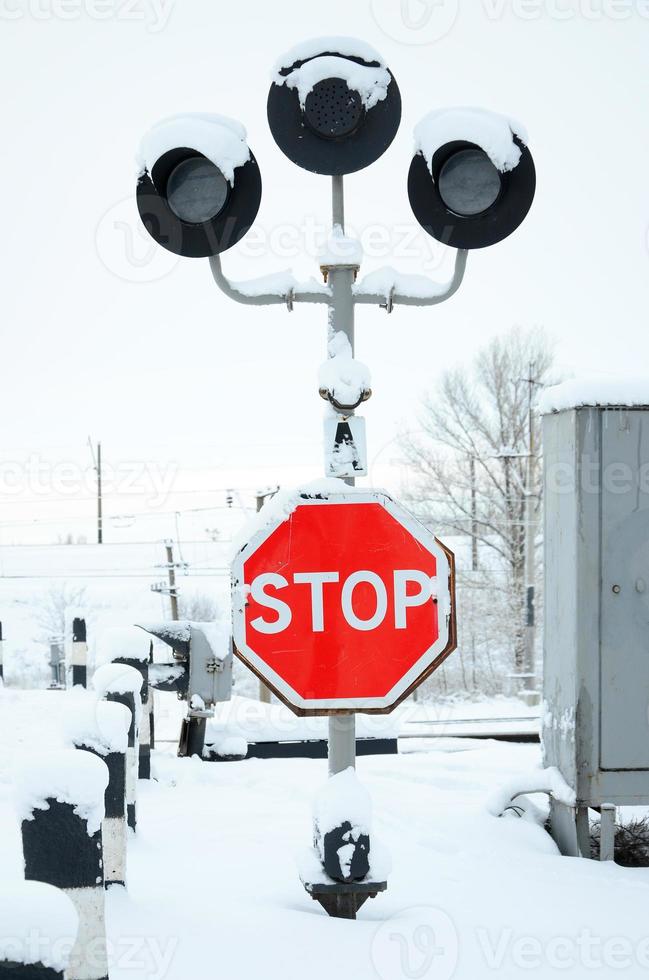 deténgase. la señal de carretera roja se encuentra en la autopista que cruza la línea ferroviaria en la temporada de invierno foto