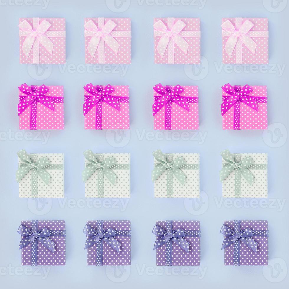 Piles of a small colored gift boxes with ribbons lies on a violet background photo