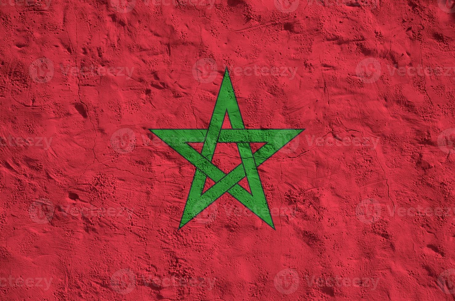 Morocco flag depicted in bright paint colors on old relief plastering wall. Textured banner on rough background photo