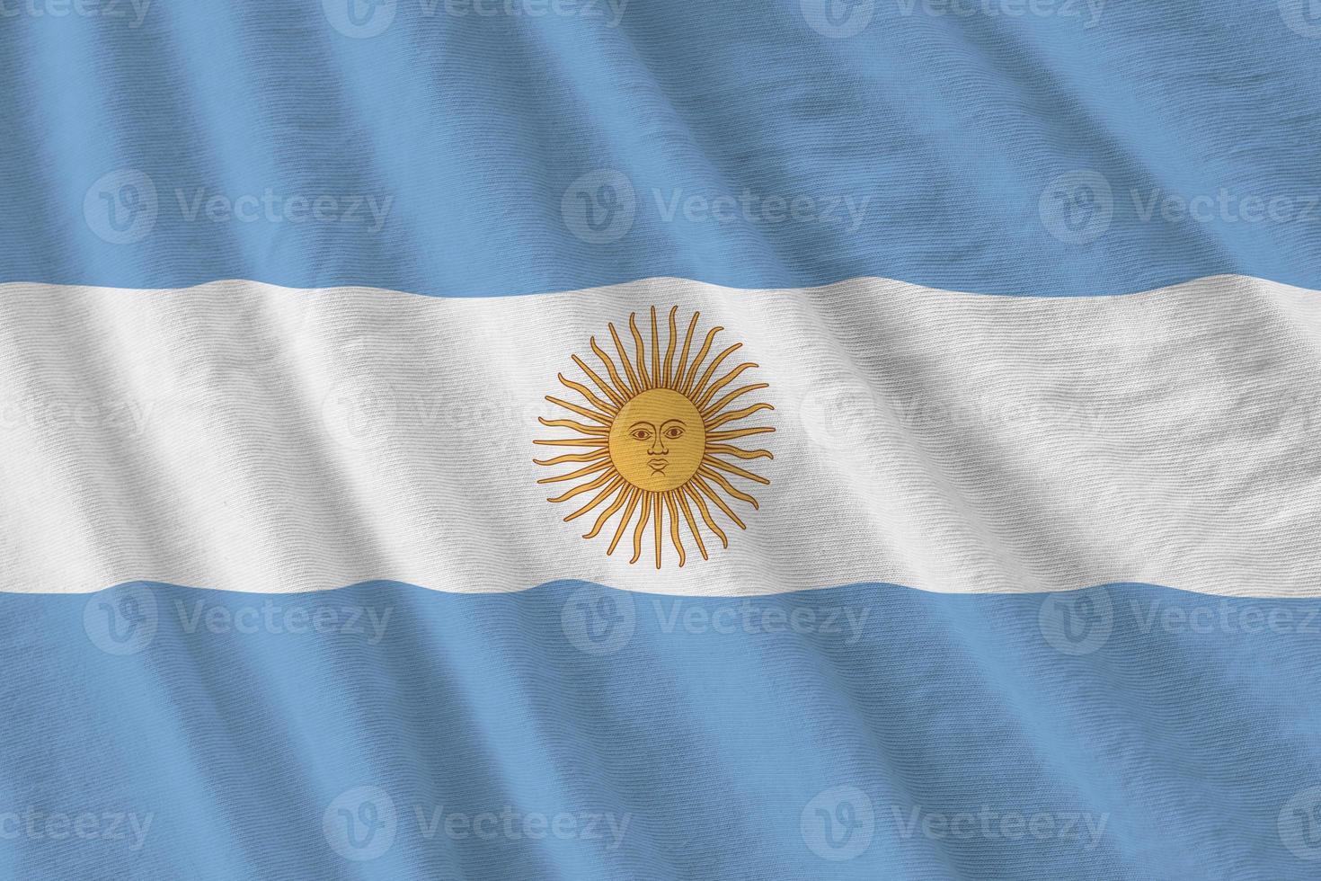 Argentina flag with big folds waving close up under the studio light indoors. The official symbols and colors in banner photo