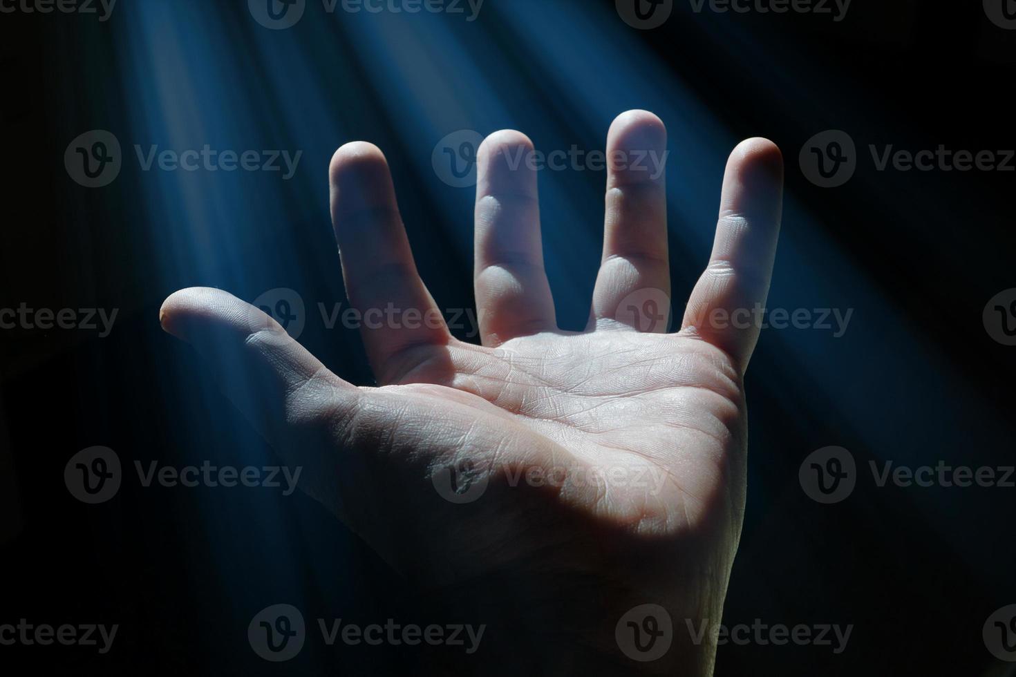 man hand up gesturing in the shadows, dark background photo