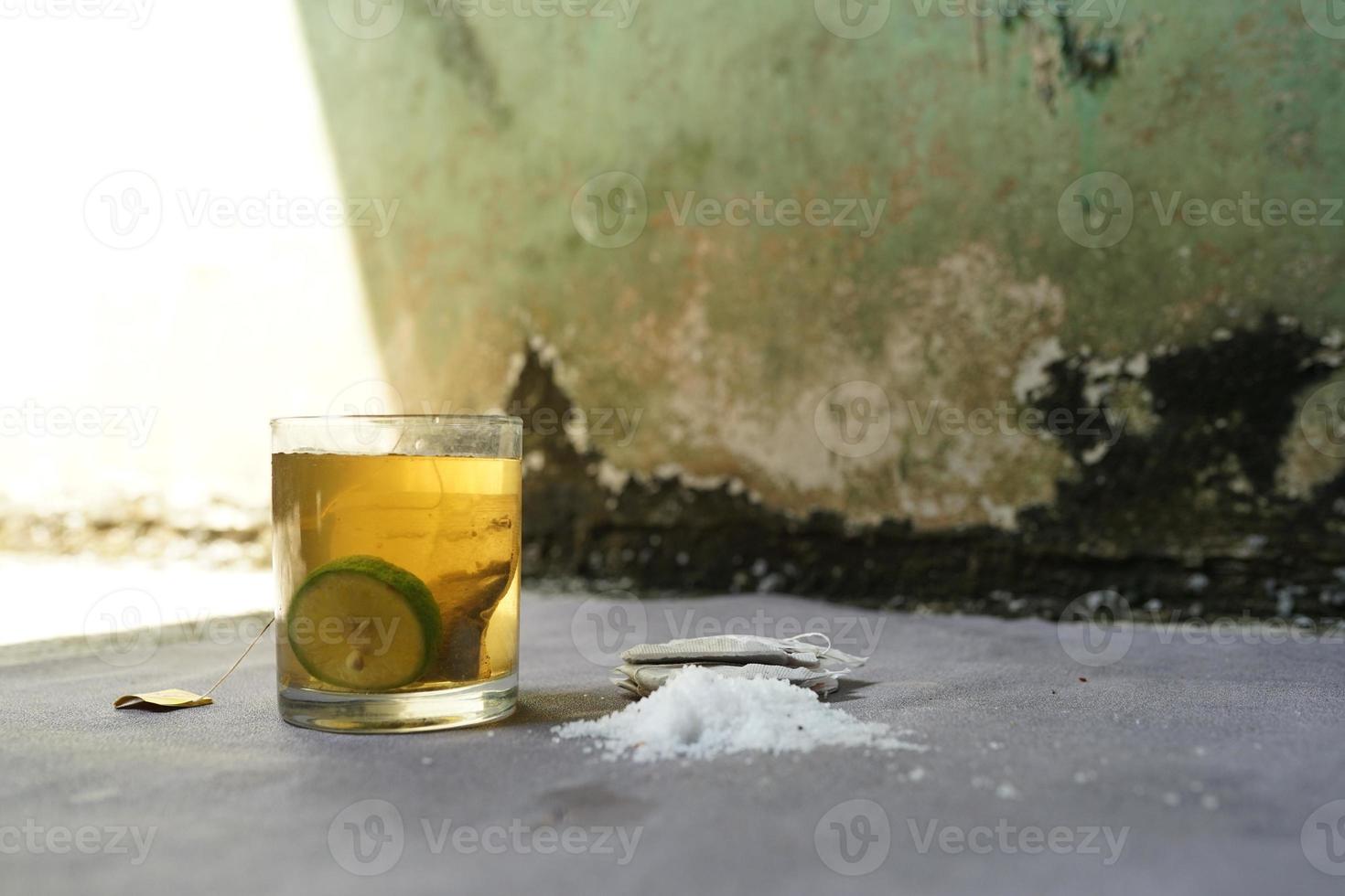 bebida fresca, té de limón de vidrio transparente sobre fondo de hormigón foto
