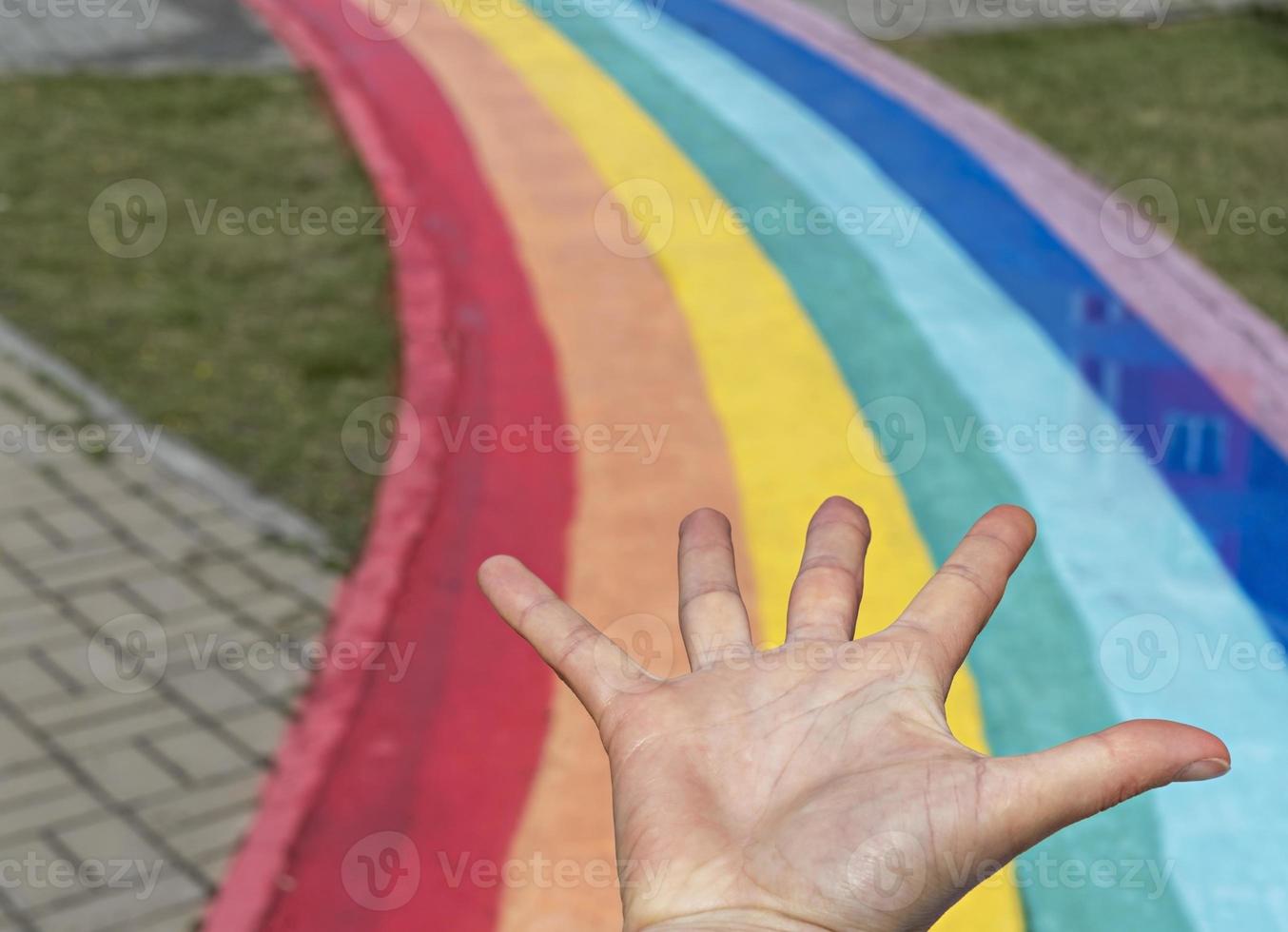 flat hand on the background of rainbow path on city street, copy space photo