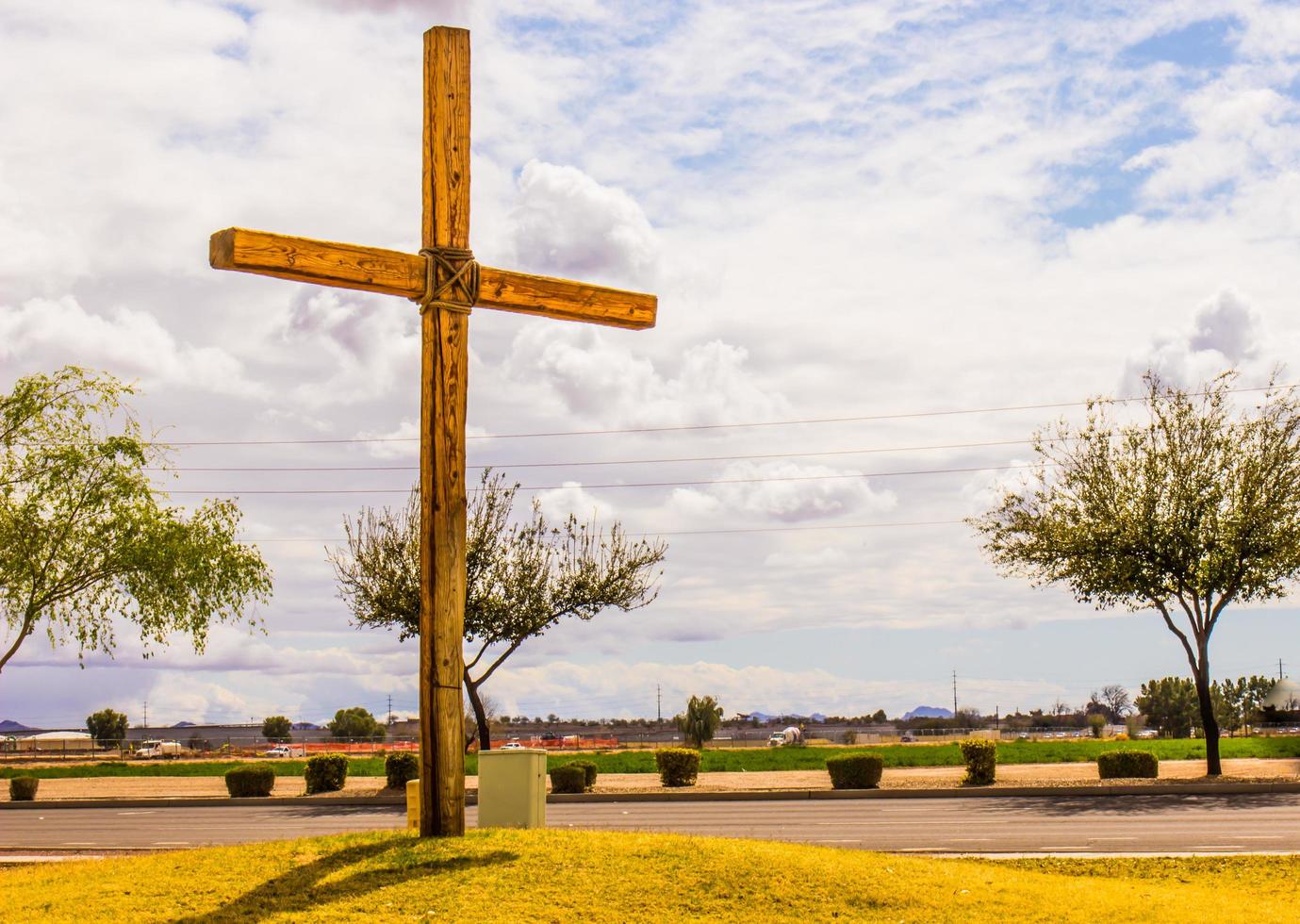 Wooden Cross On Knoll Against Cloudy Sky photo