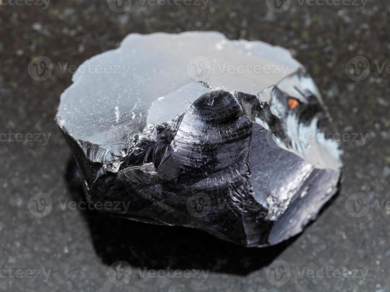cristal de vidrio volcánico de obsidiana en bruto en la oscuridad foto