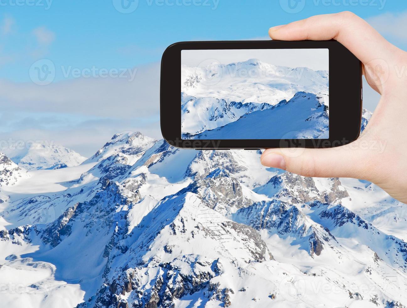 turista tomando fotos de montañas nevadas en alpes