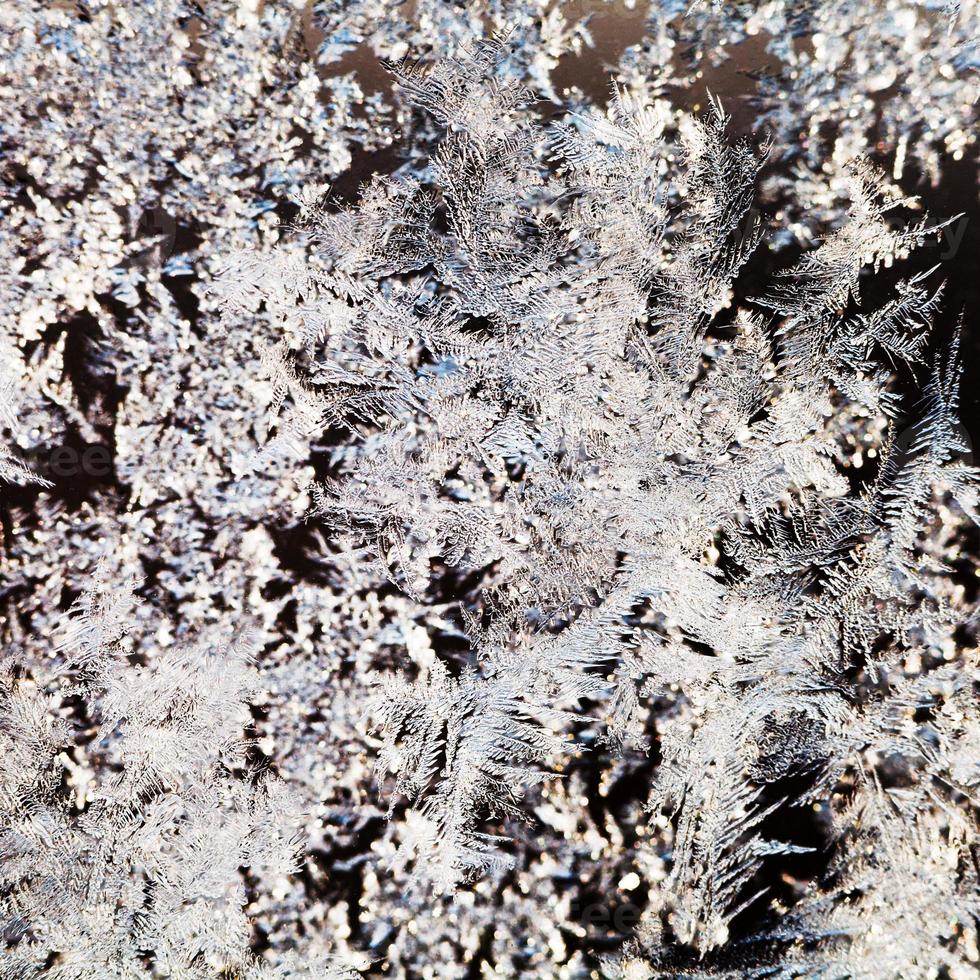 snowflakes and frost pattern on glass close up photo