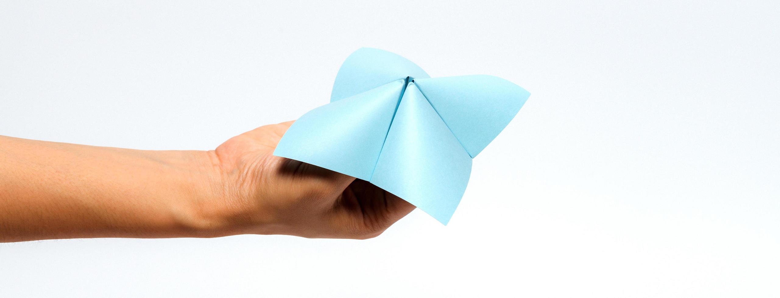 Hand in a paper fortune teller isolated on white background. photo