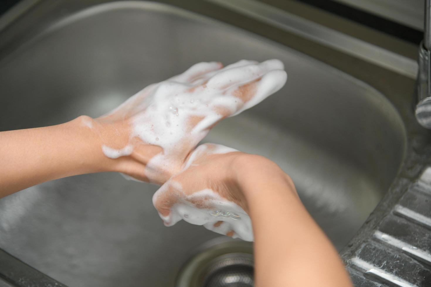Woman washing hands in a sink with tap water photo