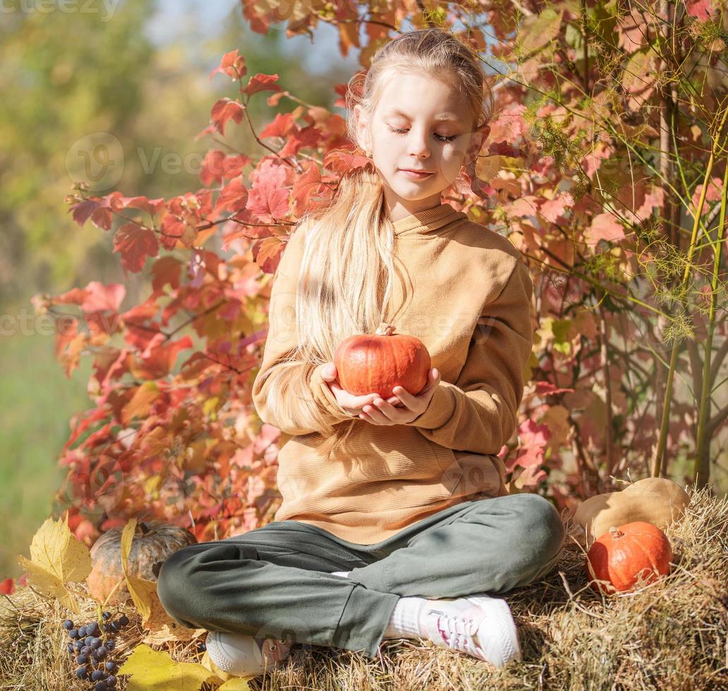 Girl in the hay with pumpkins photo