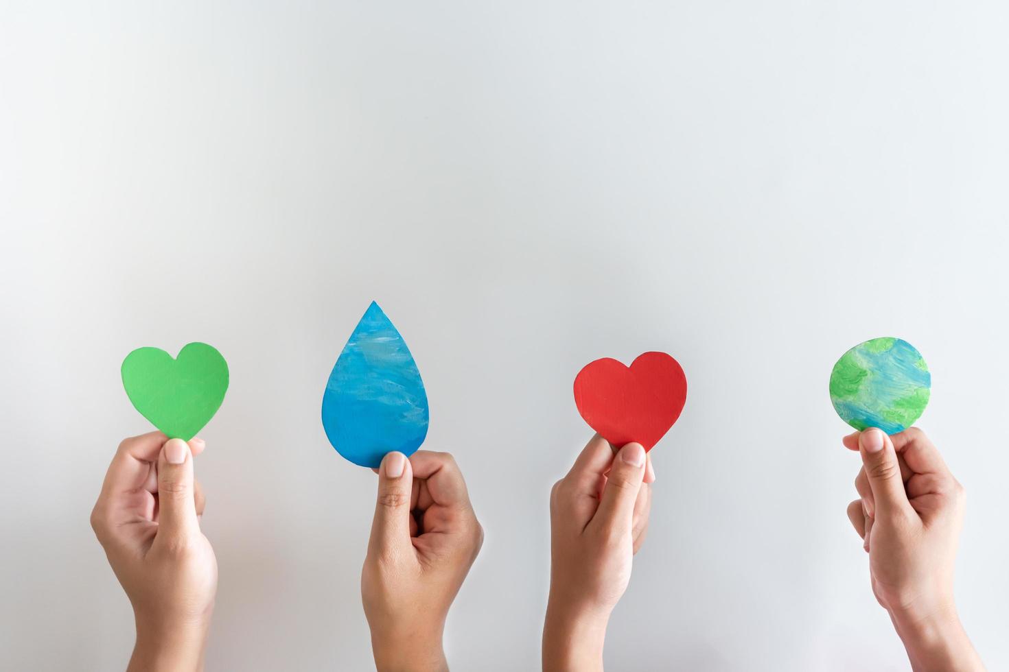 Hands holding earth, water drop, red heart and green heart shape. Concept of protecting the world from global warming with eco-heart in mind. photo