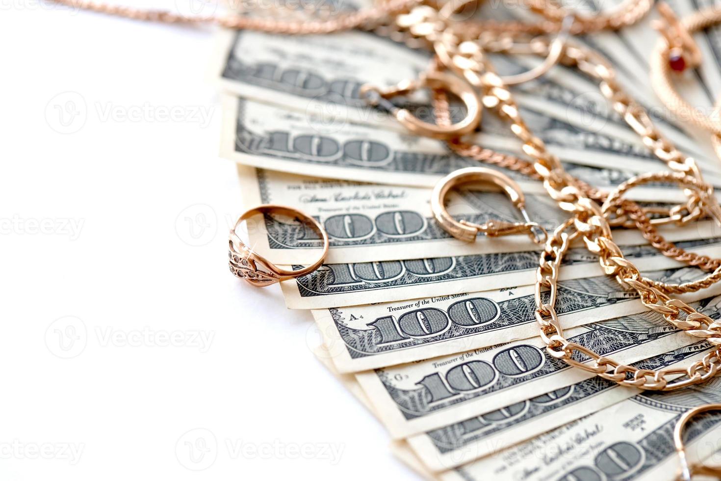 Many expensive golden jewerly rings, earrings and necklaces with big amount of US dollar bills on white background. Pawnshop or jewerly shop photo