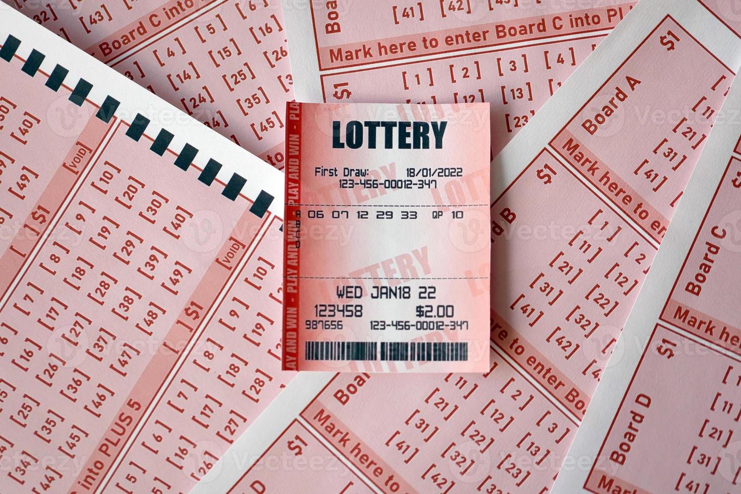 Red lottery ticket lies on pink gambling sheets with numbers for marking to play lottery. Lottery playing concept or gambling addiction. Close up photo