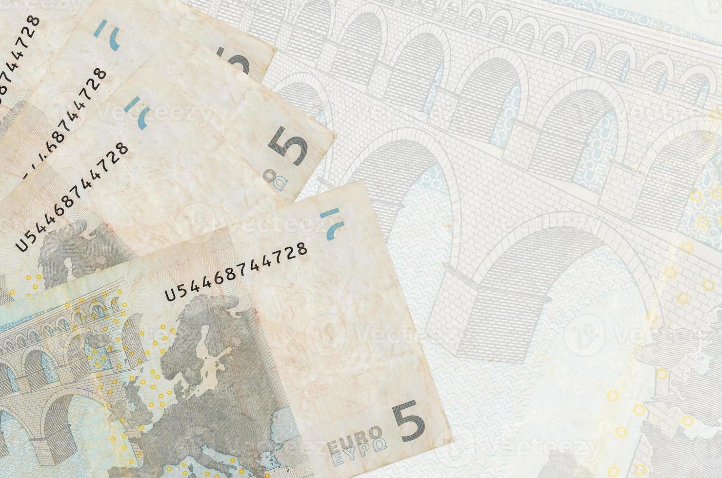 Los billetes de 5 euros se encuentran apilados sobre el fondo de un gran billete semitransparente. fondo de negocios abstracto foto